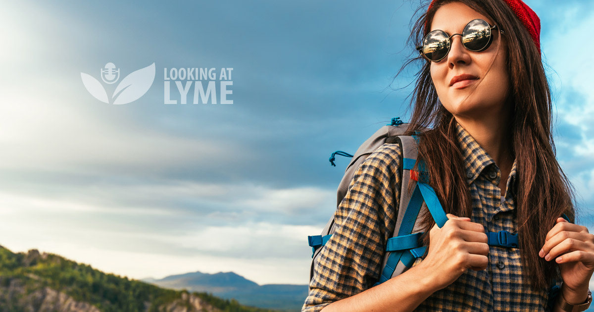A hiker wearing sunglasses looks over their shoulder into the cloudy sunset overlooking mountains and the Looking at Lyme logo.