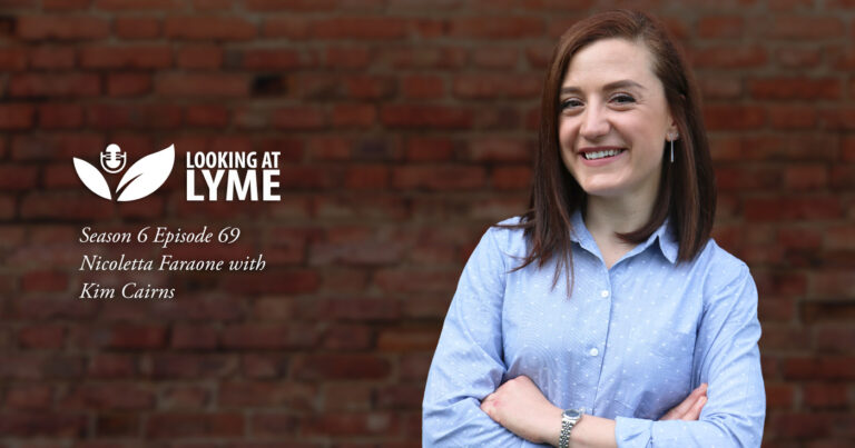 Dr. Nicoletta Faraone, a Chemical Ecologist and a Natural Product Chemist, stands smiling against a brick wall in episode 69 of Looking at Lyme.