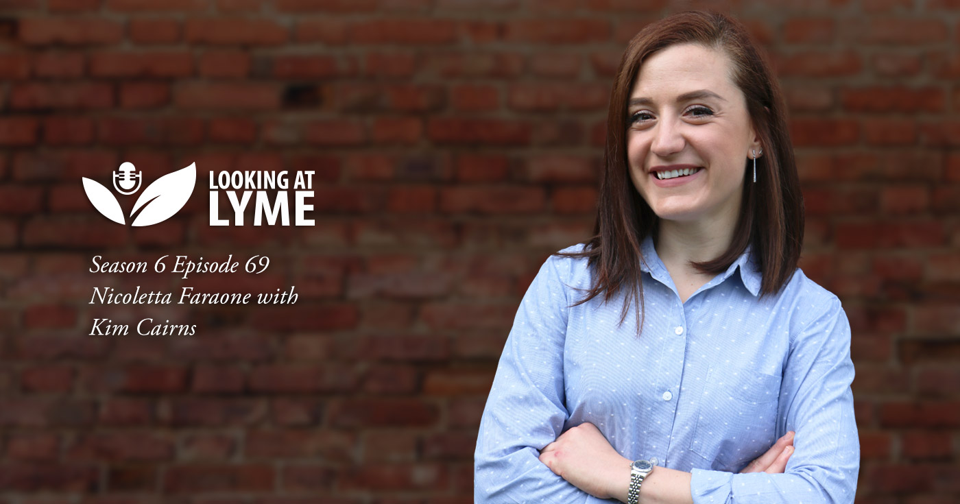 Dr. Nicoletta Faraone, a Chemical Ecologist and a Natural Product Chemist, stands smiling against a brick wall in episode 69 of Looking at Lyme.